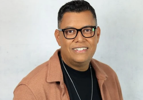 imagem do cantor gospel Anderson Freire ele está sorrindo pra câmera, de óculos preto, blusa preta por baixo e camisa aberta marrom por cima